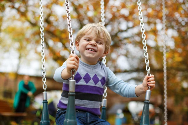 Little cute boy having fun on chain swings — Stock Photo, Image