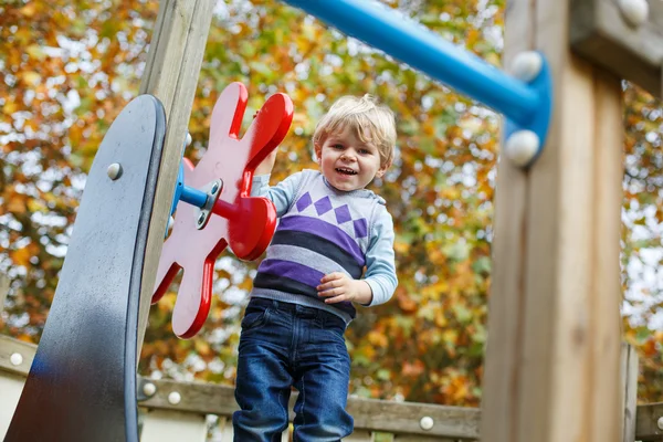 Menino criança se divertindo no playground no outono — Fotografia de Stock