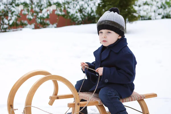 Kış gününde eski kızak üzerinde tatlı küçük çocuk — Stok fotoğraf
