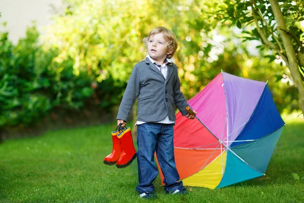 Lilla söta barn pojke med färgglada paraply och stövlar, utomhu — Stockfoto