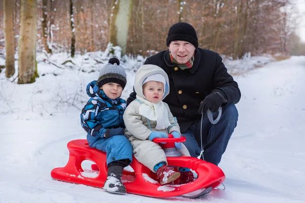 两个小的兄弟姐妹和他们的父亲在雪橇上玩耍 — 图库照片