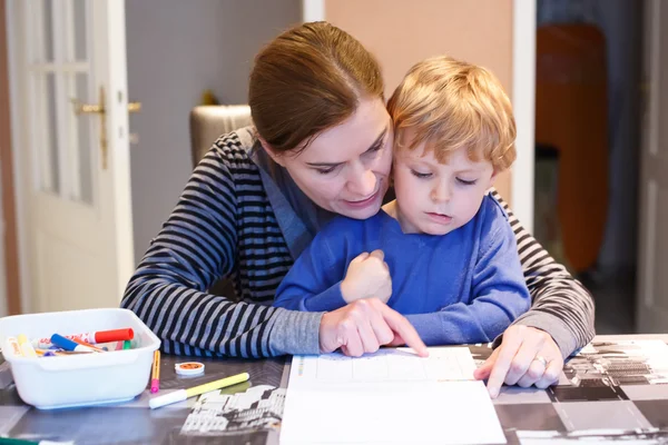 Pequeño niño rubio y su madre haciendo juntos preescolar homewo — Foto de Stock