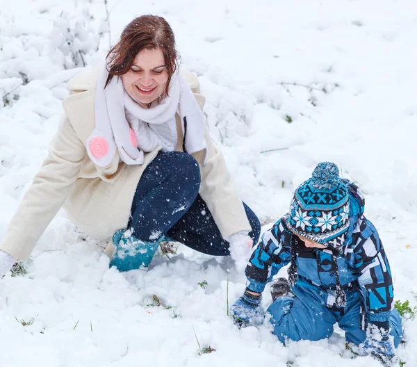 Kar kış gününde eğleniyor anne ve yürümeye başlayan çocuk — Stok fotoğraf