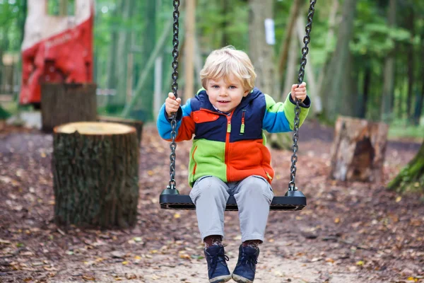 Beautiful toddler boy having fun on swing in autumn forest — Stock Photo, Image
