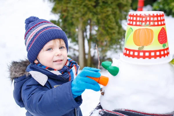 Schattig peuter jongen plezier met sneeuwpop op winterdag — Stockfoto