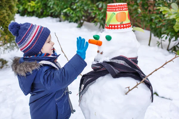 Schattig peuter jongen plezier met sneeuwpop op winterdag — Stockfoto