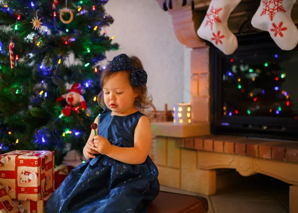 Meisje met lolly en kerstboom en decoratie — Stockfoto