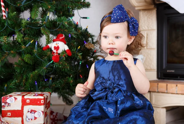 Meisje met lolly en kerstboom en decoratie — Stockfoto