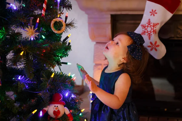 Niña feliz por el árbol de navidad y las luces — Foto de Stock