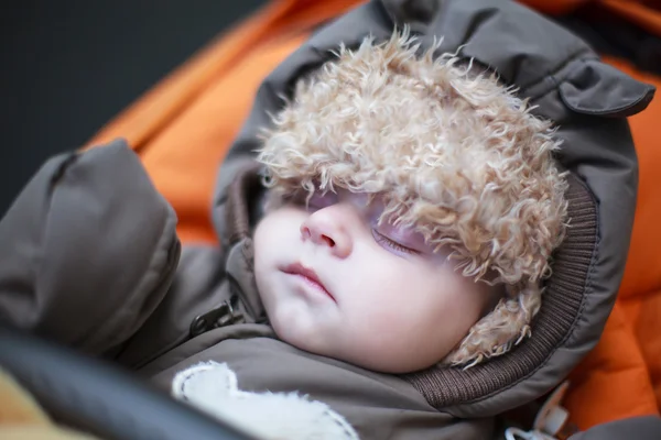 Очаровательный мальчик в зимней одежде спит в коляске — стоковое фото