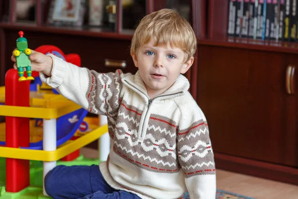 Piccolo ragazzo biondo di tre anni che gioca con i giocattoli a casa — Foto Stock