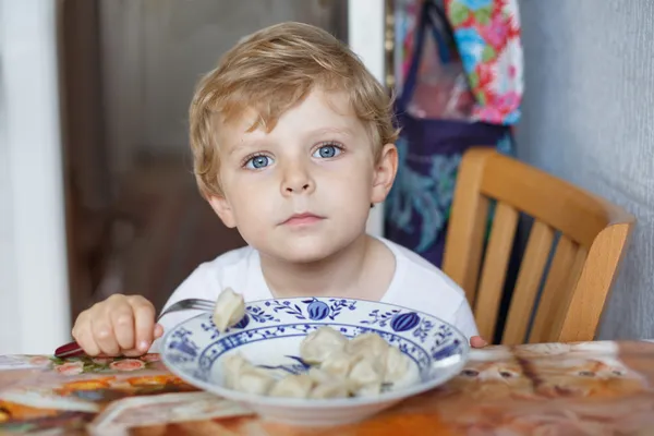Bonito menino de três anos comendo macarrão em casa cozinha — Fotografia de Stock