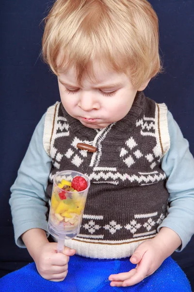 Little toddler boy eating fruit salad in push up cake form. — Stock Photo, Image