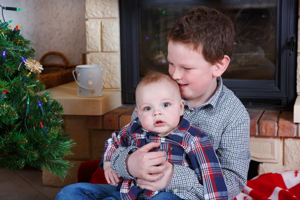 学校の男の子と愛らしい赤ちゃん男の子クリスマス装飾と屋内 — ストック写真