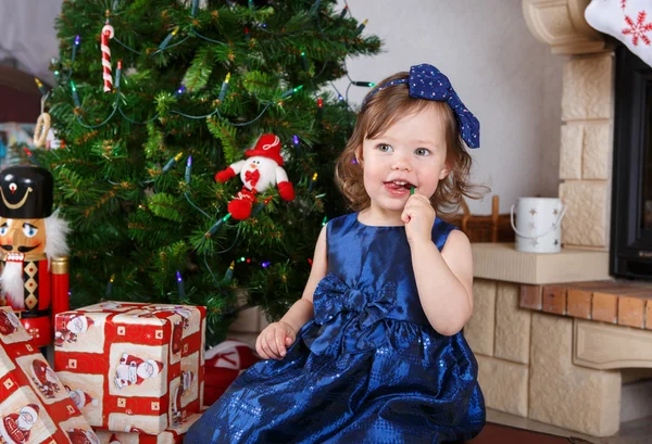 Meisje met lolly en kerstboom en decoratie — Stockfoto