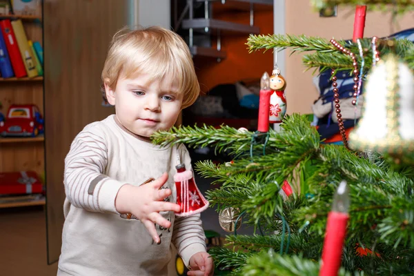 Menino loiro decorando a árvore de Natal em casa . — Fotografia de Stock