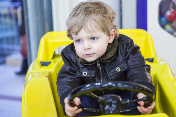 Petit garçon tout-petit sur la voiture sur l'aire de jeux — Photo
