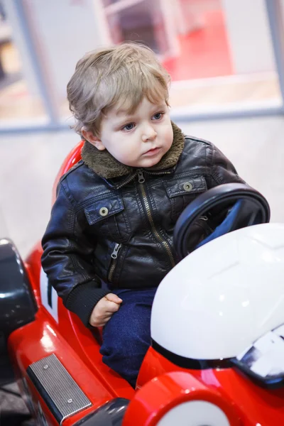 Petit garçon tout-petit sur la voiture sur l'aire de jeux — Photo