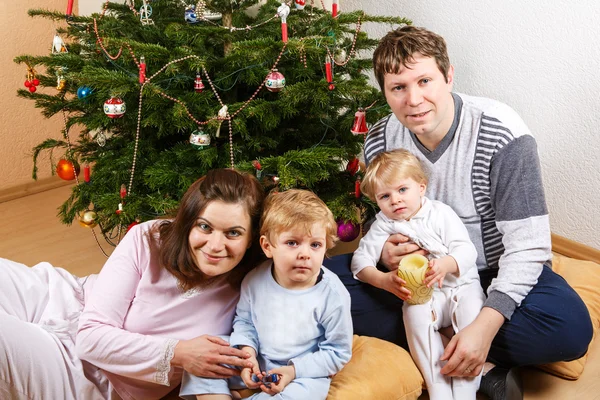 Jovem família feliz de quatro pessoas na árvore de Natal  . — Fotografia de Stock