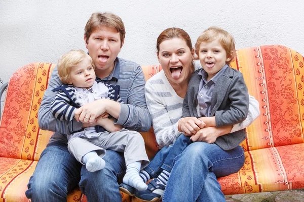 Vierköpfige Familie sitzt auf Bank im Haus — Stockfoto