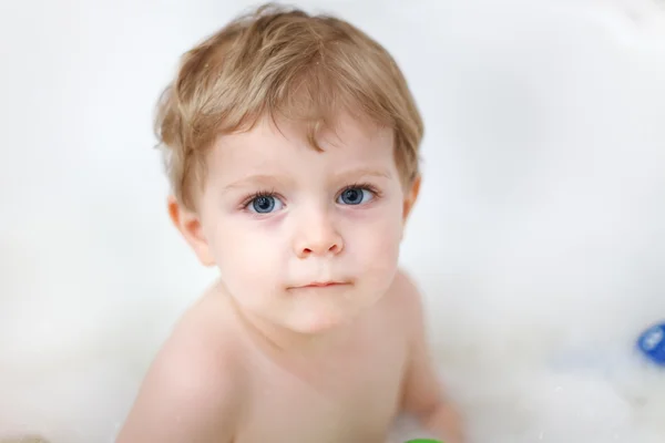 Adorable blond toddler boy having fun with water by taking bath — Stock Photo, Image