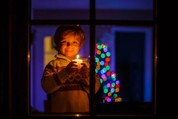 Little boy standing by winter at Christmas time and holding cand — Stock Photo, Image