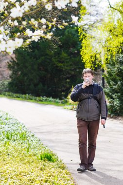 çiçekli WHI ile parkta yürüyüş ve içme kahve genç adam