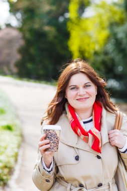 yürüyüş ve içme kahve çiçekli w ile parkta genç kadın