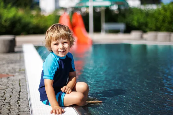 Cute toddler playing with water by the outdoor swimming pool — Stock Photo, Image