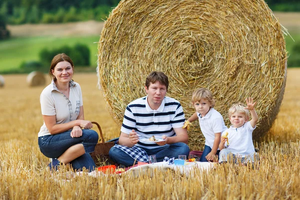 Lycklig familj av fyra picknick på gula hö fältet i sommar. — Stockfoto