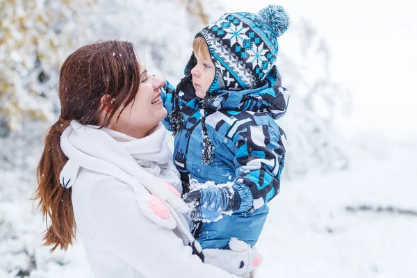 Poco niño preescolar y su madre jugando con la primera nieve en p —  Fotos de Stock