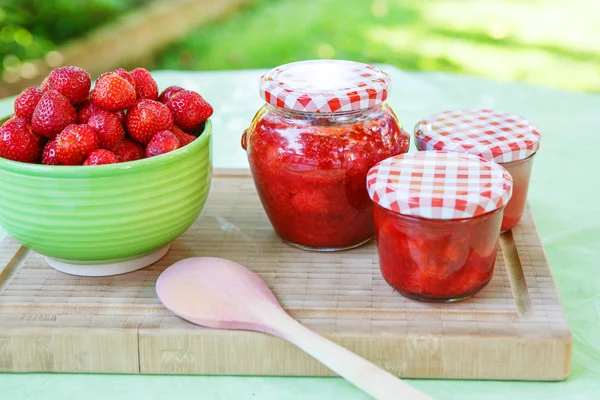 Mermelada de fresa casera en diferentes frascos y fresa fresca madura —  Fotos de Stock