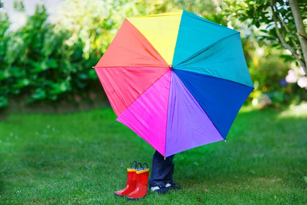 Little cute toddler boy with colorful umbrella and boots, outdoo — Stock Photo, Image