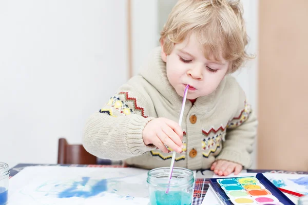 Söta barn pojke ha roligt inomhus, målar med olika smärta — Stockfoto