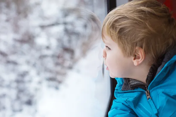 Mignon petit garçon regardant par la fenêtre du train — Photo