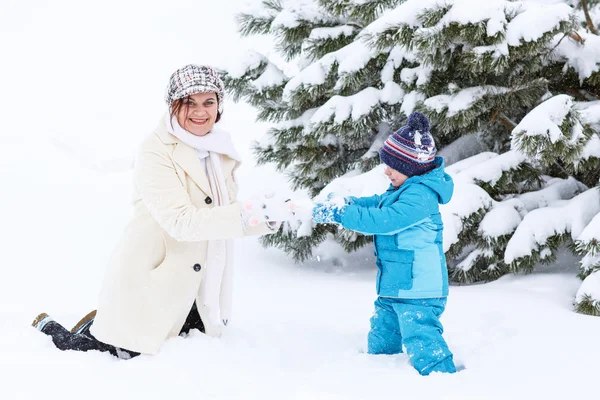 Liten förskola pojke och hans mamma leker med första snön i p — Stockfoto