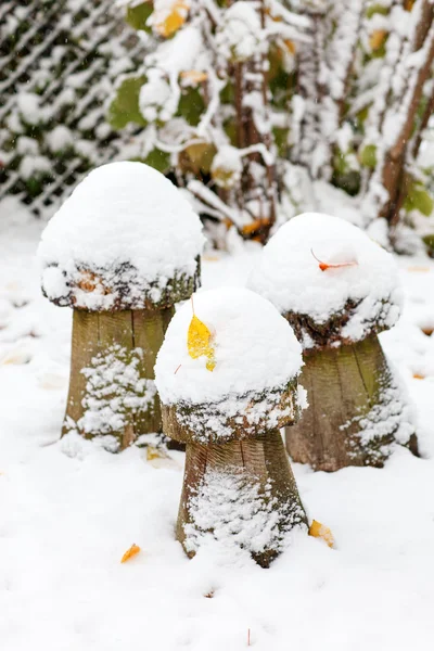 Wooden mushroom decoration during snowfall in winter garden. — Stock Photo, Image