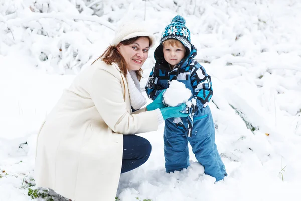 Мати і маленький хлопчик розважаються зі снігом в зимовий день — стокове фото