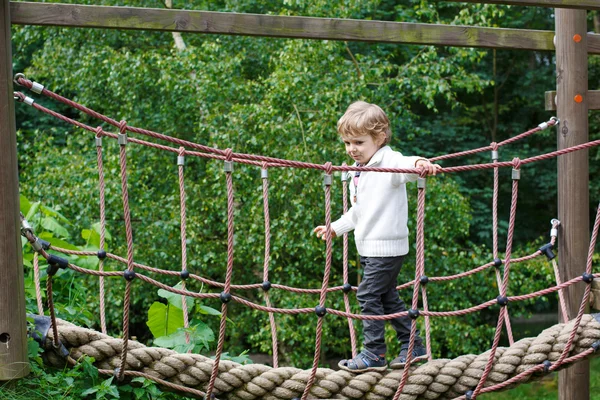 Niedliche kleine Kleinkind Junge mit Spaß beim Klettern auf Spielplatz i — Stockfoto