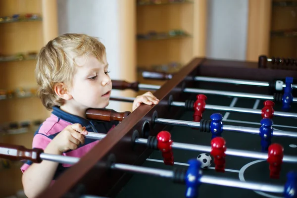 Küçük sarışın çocuk evde tahta masa futbol oynamak. — Stok fotoğraf