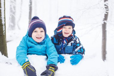 mutlu bir aile: iki küçük ikiz erkek eğleniyor kar winte içinde