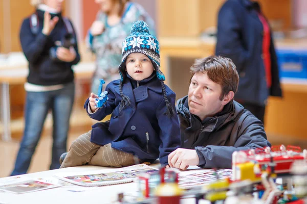 Père et petit fils s'amusent sur l'exposition de jouets, à l'intérieur . — Photo