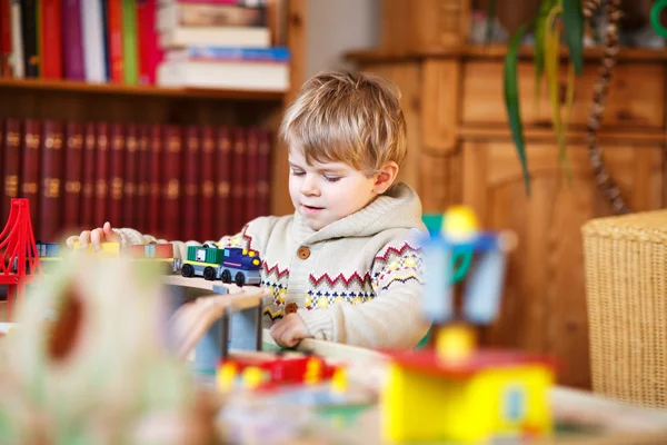 Piccolo bambino che gioca con la ferrovia di legno, in casa — Foto Stock