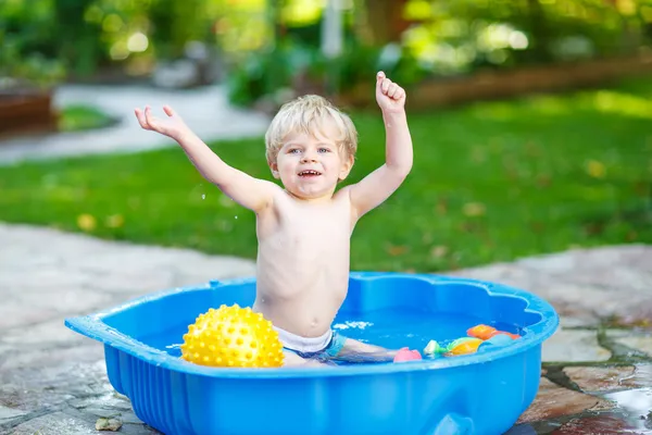 Menino pequeno se divertindo com água espirrando no verão gar — Fotografia de Stock