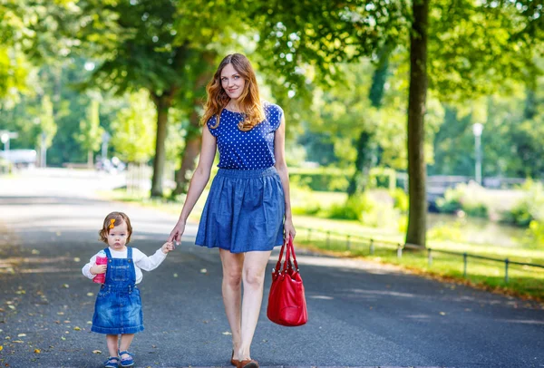 Young woman and little girl of one year walking through summer p — Stock Photo, Image