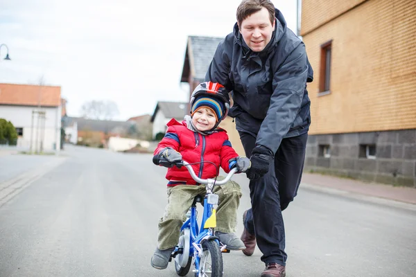 Joven padre enseñando a su hijo pequeño de 3 años a andar en bicicleta —  Fotos de Stock