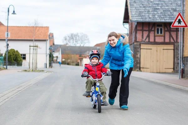 Joven madre enseñando a su hijo pequeño de 3 años a montar en bicicleta —  Fotos de Stock