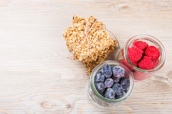 Zdravé pozadí: dřevěný stůl s granola obilovin bary a s — Stock fotografie