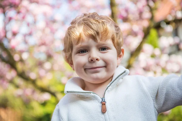 Portret van kleine jongen met bloeiende boom op achtergrond — Stockfoto