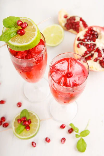 Due bicchieri con pomgranato rosso champagne, lime e menta . — Foto Stock